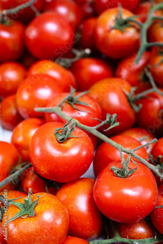 A bunch of ripe red tomatoes are piled on top of each other. The tomatoes are all different sizes and are arranged in a way that they are all visible. Concept of abundance and freshness