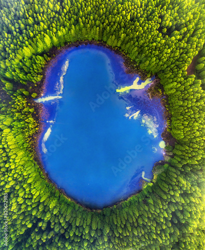 Aerial top down amazing lake of round shape. Cloudy sky reflected in clear turquoise water of pond surrounded by trees and plants. Ripple on water surface,  - Sete Cidades