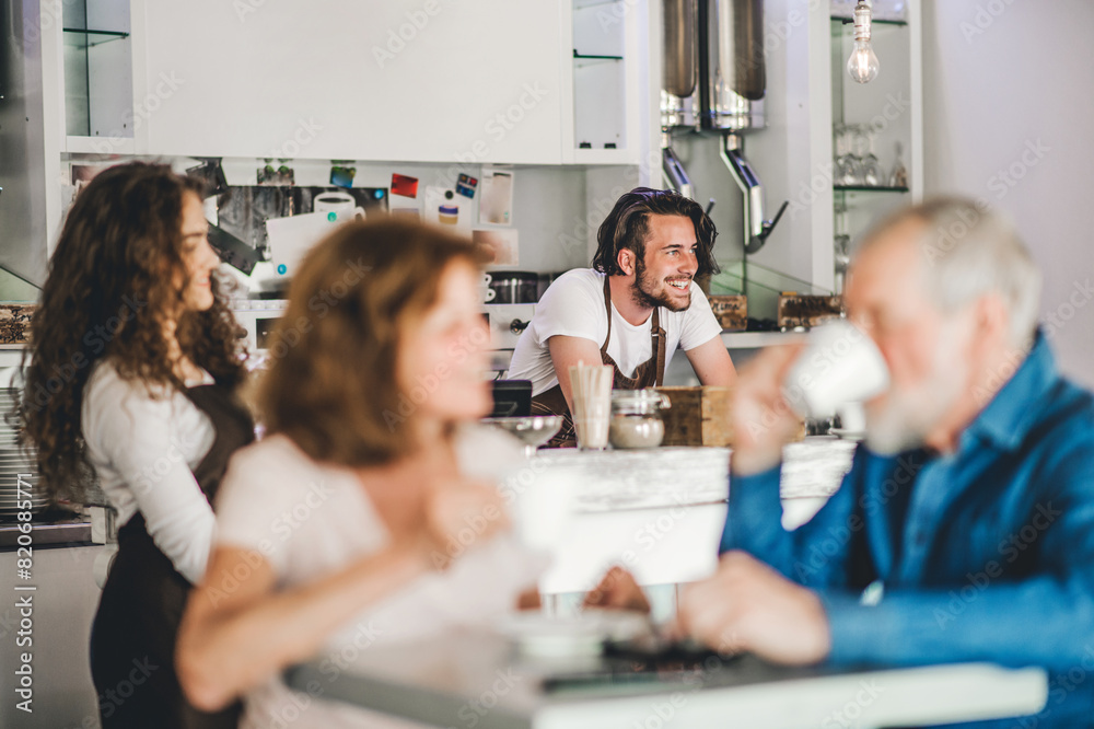 Handsome barista working in coffee shop, serving customers, elderly couple. University student working part-time in cafe. Handsome barista working in coffee shop, serving customers, elderly couple. University student working part-time in cafe.