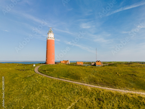 A majestic lighthouse stands tall on a grassy field  casting a watchful eye over the Texel landscape below.