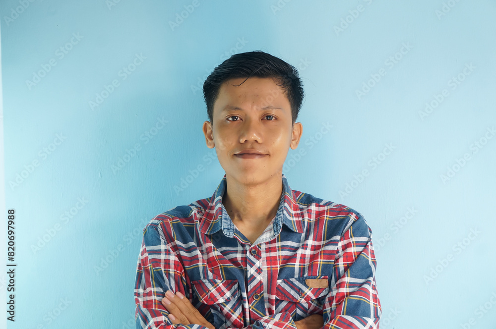 Smiling young asian man wearing a plaid shirt looking at the camera Smiling young asian man wearing a plaid shirt looking at the camera