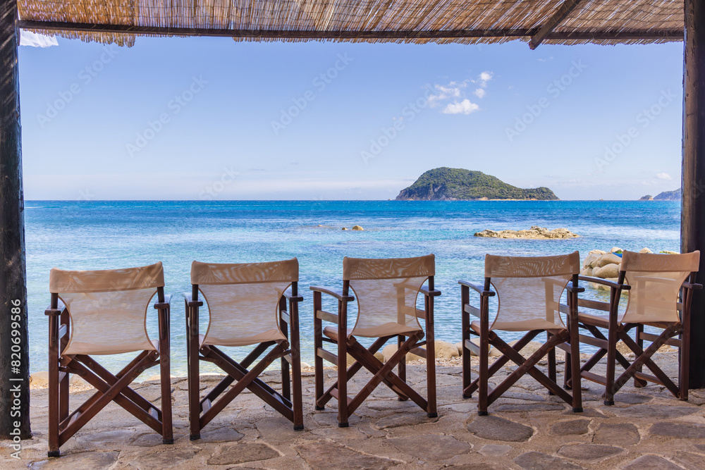 A row of chairs on the beach overlooking the Ionian sea with Turtle Island in the background, Zakynthos, Greece A row of chairs on the beach overlooking the Ionian sea with Turtle Island in the background, Zakynthos, Greece