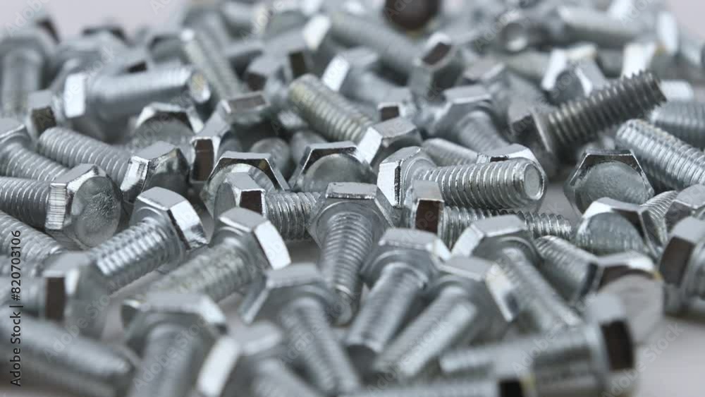 A scattered of stainless M6 threaded bolts. Movement with rotation. Close-up, side view, small depth of field. A scattered of stainless M6 threaded bolts. Movement with rotation. Close-up, side view, small depth of field.