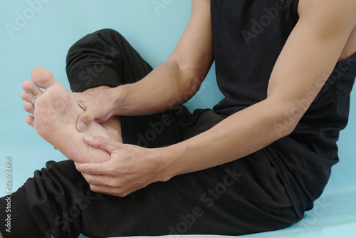 Asian man feels pain in his leg. Gently massage the sore leg with his hand photo