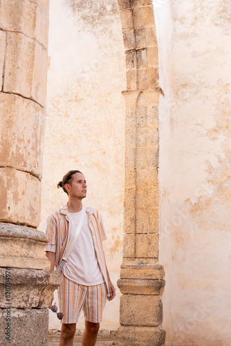 Young Adult Exploring Ancient Ruins in Striped Summer Attire During Golden Hour