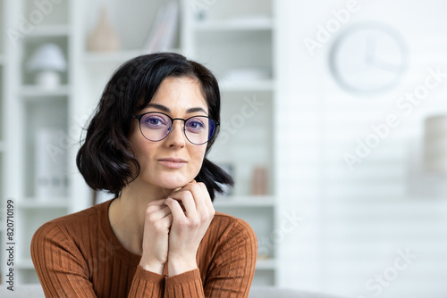 Free Download Confident woman with glasses sitting at home, looking at camera - GFXLoad