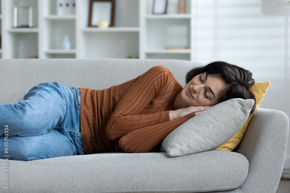 Young woman resting on a grey sofa in a cozy living room at home Young woman resting on a grey sofa in a cozy living room at home