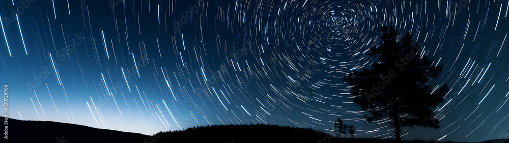 Long-exposure shot of star trails in a night sky, with a silhouetted ...