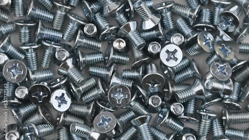 A scattered of metric countersunk M6 threaded bolts. Movement with rotation. Close-up, flat lay, top view. photo