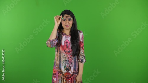 Beautiful Indian girl with specs making different faces on the green screen - isolated  human expressions concepts. A pretty girl acting all confused about something in front of the camera - disgus... photo