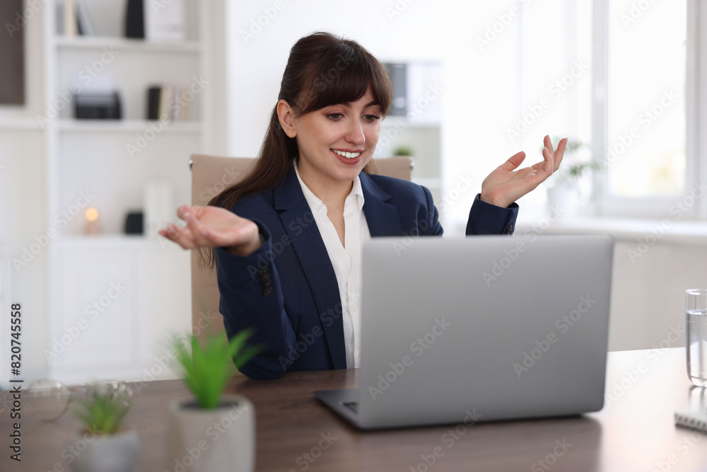 Woman using video chat during webinar at wooden table in office