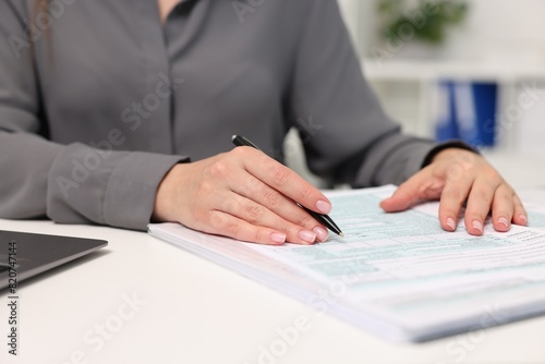 Secretary doing paperwork at table in office, closeup