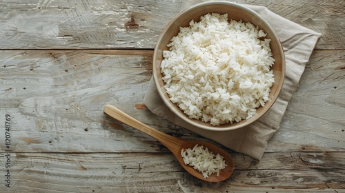 A bowl filled with white rice sits next to a wooden spoon on a table. Generative AI