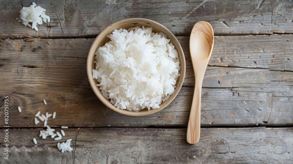 A wooden bowl filled with cooked white rice sits next to a wooden spoon on a wooden table. Generative AI A wooden bowl filled with cooked white rice sits next to a wooden spoon on a wooden table. Generative AI