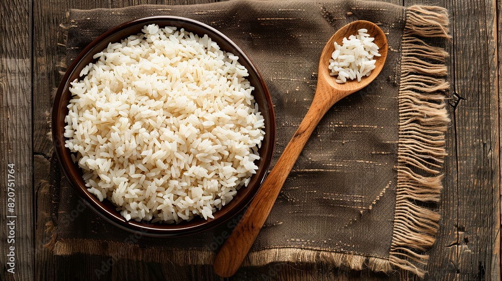 A bowl of cooked white rice sits on a wooden table next to a wooden spoon, ready to be enjoyed. Generative AI A bowl of cooked white rice sits on a wooden table next to a wooden spoon, ready to be enjoyed. Generative AI