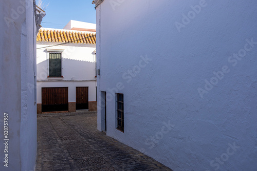 The contrasting shadows play across the facade of a traditional whitewashed building in a cobblestone street of Carmona, Andalusia, Spain photo