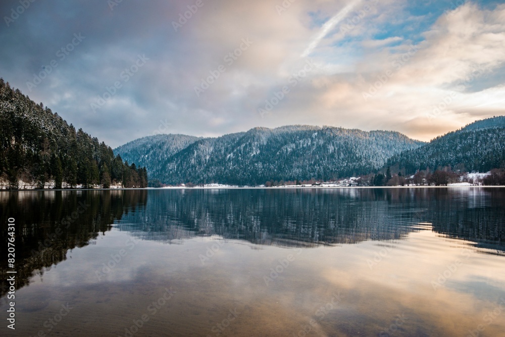 Fototapeta premium a river with snowy mountains in the background, and trees at the bank