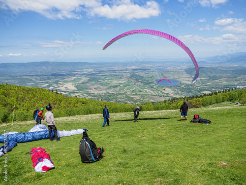 A paraglider pilot starts the takeoff while his colleagues check that the glider has inflated perfectly.