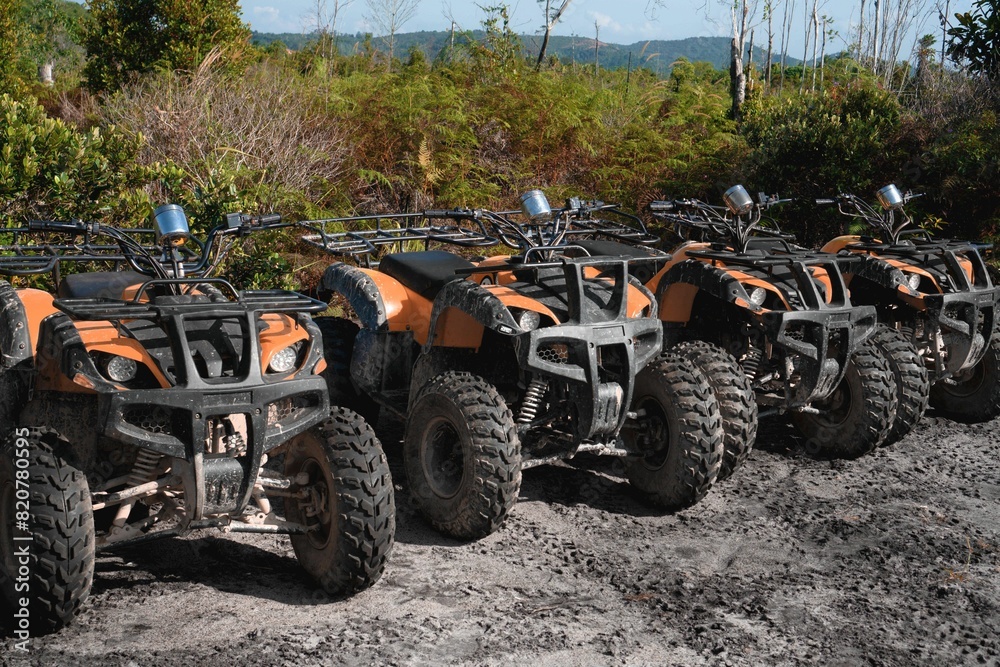 Fototapeta premium Row of four-wheeler all-terrain vehicles parked on a dirt road