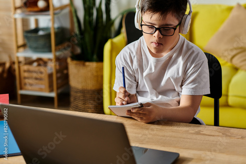 Foto A adorable boy with Down syndrome is engrossed in using a laptop and wearing headphones at a table