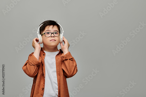 Charming boy with Down syndrome blissfully listens to music on headphones.