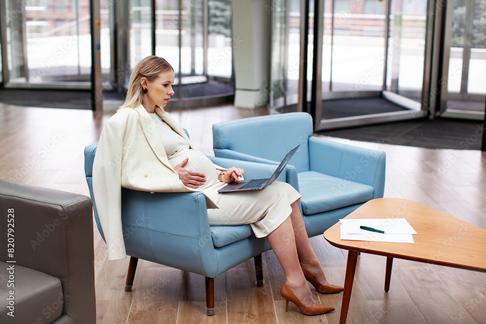 Beautiful pregnant businesswoman working indoors with a laptop. Pregnant female entrepreneur multitasking in office space, managing business tasks with professionalism and efficiency Beautiful pregnant businesswoman working indoors with a laptop. Pregnant female entrepreneur multitasking in office space, managing business tasks with professionalism and efficiency