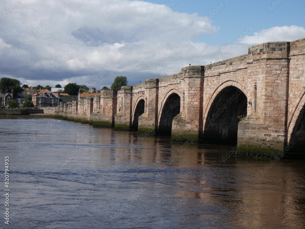 an arch shaped brick bridge across the water in the middle of town an arch shaped brick bridge across the water in the middle of town