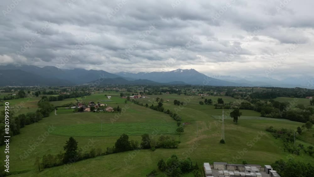Aerial video of a small village and fields with mountains in the background on a cloudy day Aerial video of a small village and fields with mountains in the background on a cloudy day