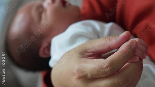 Closeup Of Mother's Hand Gently Touched Hand Of The Baby Sleeping In Her Arms