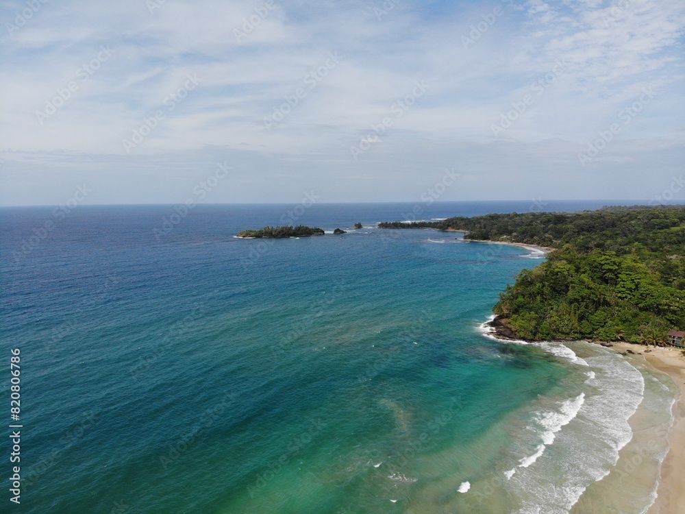 Aerial view of a turquoise sea against a lush green tropical island Aerial view of a turquoise sea against a lush green tropical island