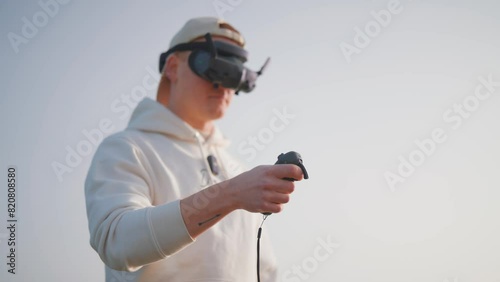 Unmanned aircraft pilot use goggles and rc motion remote to fly FPV drone photo