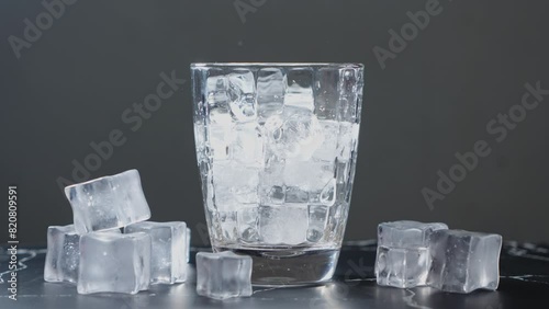 Throw ice cubes in empty glass. Ice Cubes falling down in empty transparent glass. Make a fresh drink. Footage b roll scene 4k. Slow motion.