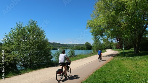 Cyclotourisme au bord du lac du chanoine Kir à Dijon, en Côte d’Or / Bourgogne, paysage de nature avec deux cyclistes roulant sur une piste cyclable au bord de l'eau (France) photo