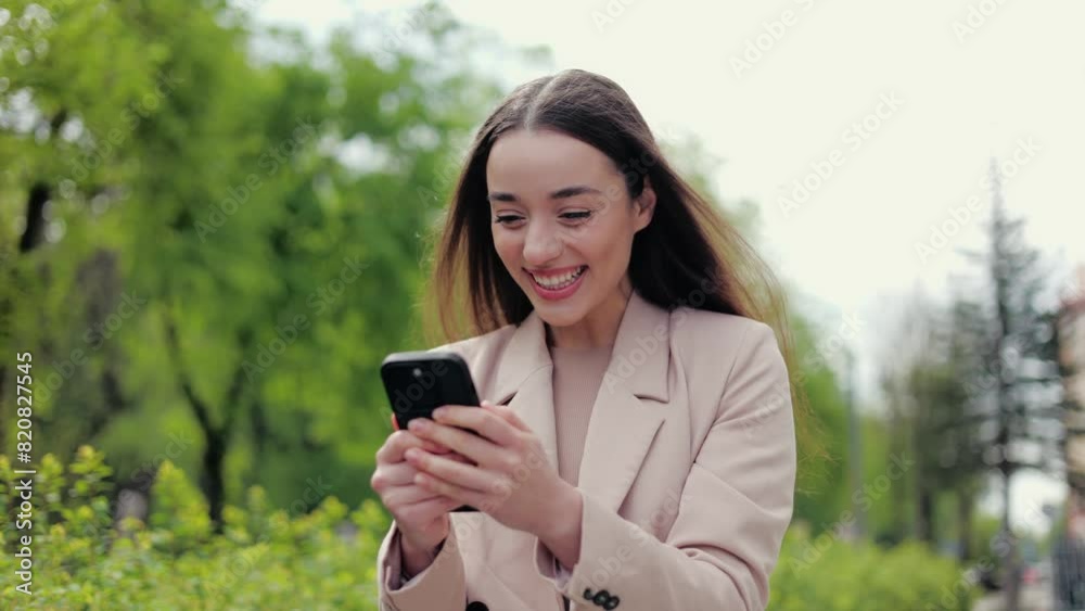 Cheerful european woman carrying cellphone in hands and getting excited by received message with pleasant news. Ecstatic female shaking device and raising head up for expressing positive emotions. Cheerful european woman carrying cellphone in hands and getting excited by received message with pleasant news. Ecstatic female shaking device and raising head up for expressing positive emotions.