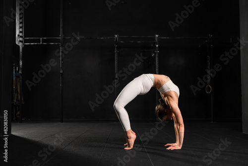 Woman doing acroyoga alone, solo. Flexibile woman focusing on yoga and acrobatics, preparing for partner exercises.