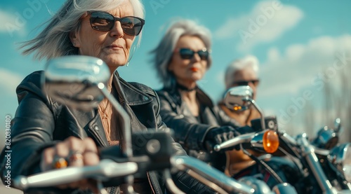 Group of elegant elderly women wearing sunglasses and leather jackets riding on motorcycles. photo