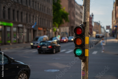 Traffic light in medium level showing colors with cars and street in the background for transport in Riga, Latvia