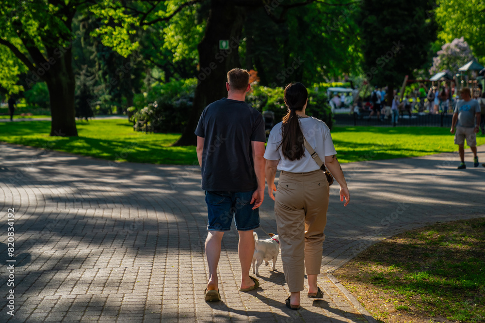 People walking in park at Riga, Latvia during summer time with their pet dog People walking in park at Riga, Latvia during summer time with their pet dog