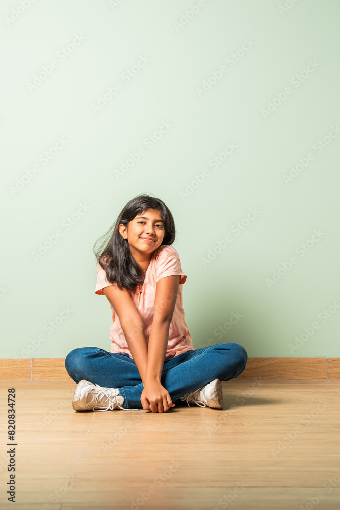 Asian Indian teenager girl child looking at camera while sitting on floor Asian Indian teenager girl child looking at camera while sitting on floor
