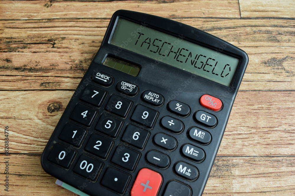 Concept of Learning language - German. Taschengeld it means pocket money written on Calculator. German language isolated on Wooden Table. Concept of Learning language - German. Taschengeld it means pocket money written on Calculator. German language isolated on Wooden Table.