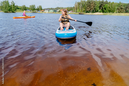 A woman is paddling a board in a lake surrounded by water and sky