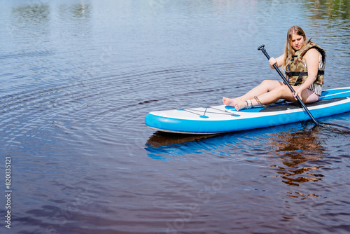 A woman on a paddle board in water holding a paddle
