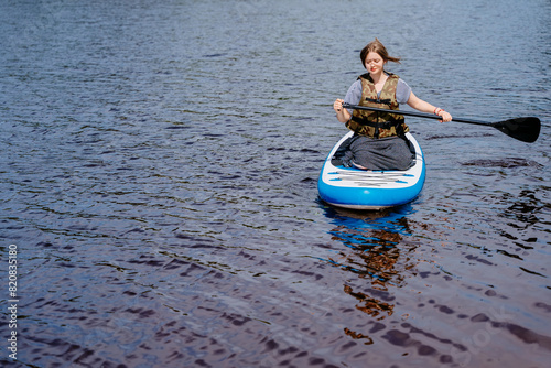 A woman is enjoying paddle boarding on a serene lake on a sunny day