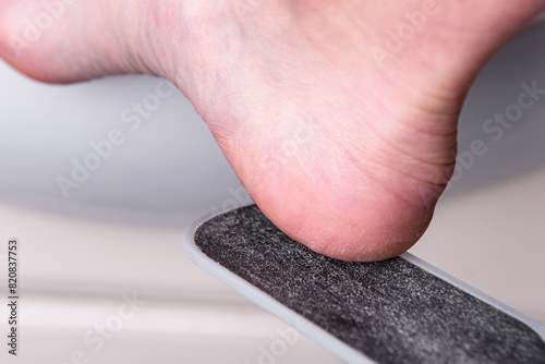 Woman's hands cleaning the heel with pumice in the bathroom.