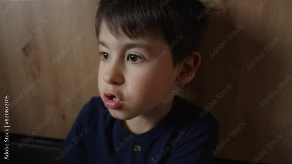 A young boy is gazing out of a window as he sits in front of it A young boy is gazing out of a window as he sits in front of it