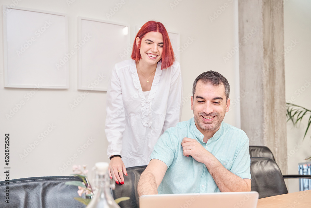 Fototapeta premium business couple looking at the laptop screen while laughing
