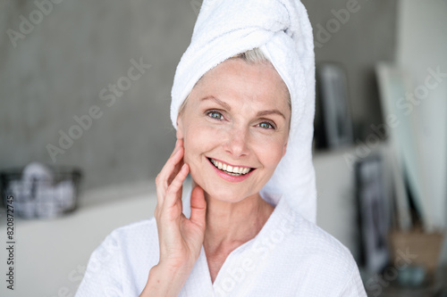 Smiling mature woman in bathrobe feeling refreshment after shower