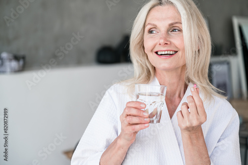 50s old woman taking capsule with Omega 3, nutrition concept © brizmaker