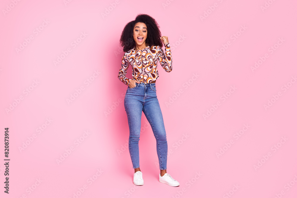 Full length photo of lucky pretty lady dressed print shirt rising fist empty space isolated pink color background Full length photo of lucky pretty lady dressed print shirt rising fist empty space isolated pink color background