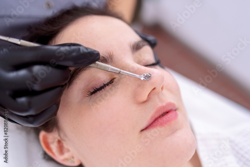 Cosmetologist makes cleaning in forehead of caucasian woman